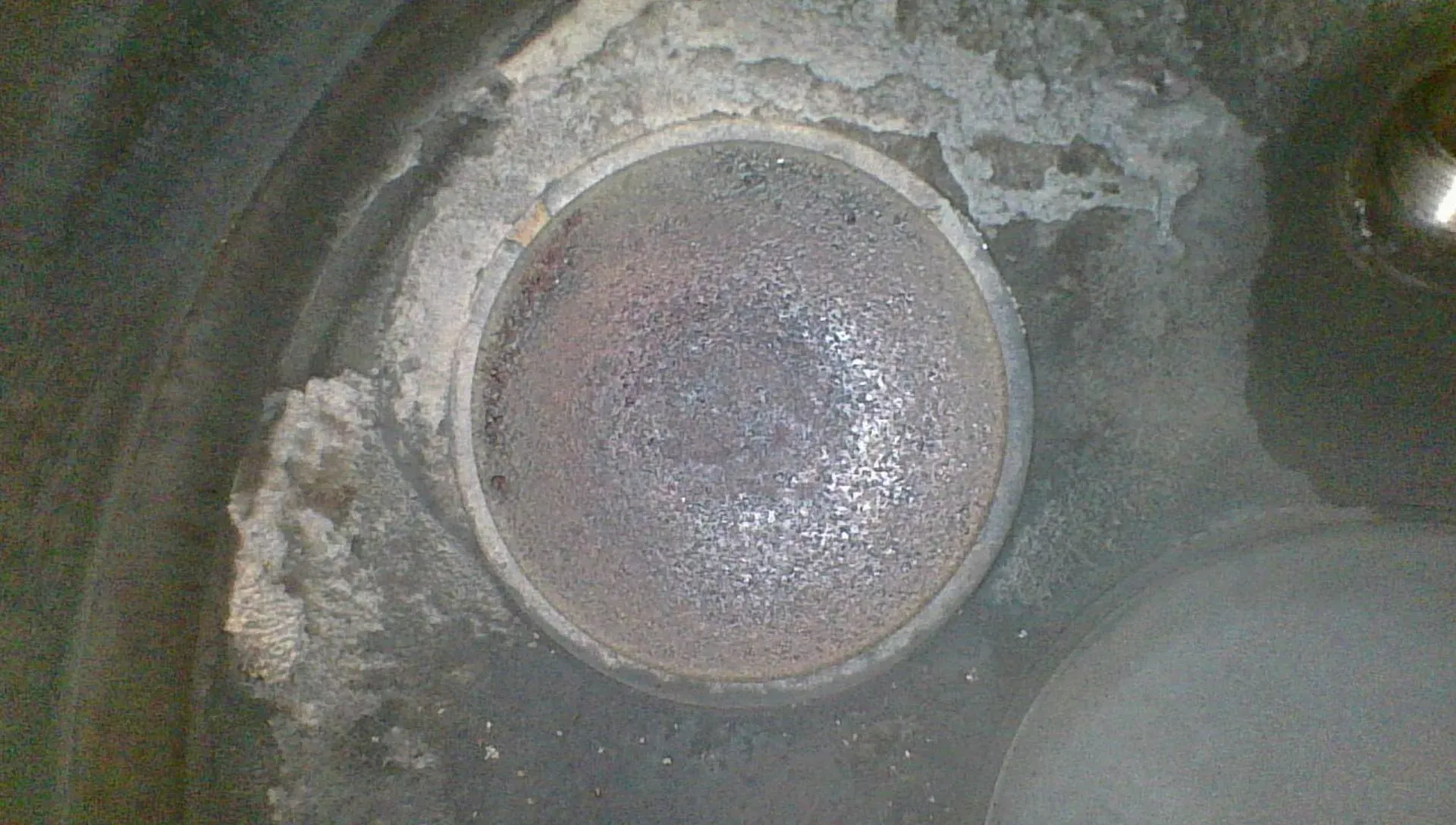 Borescope view of the closed exhaust valve face showing a reddish-tan concentric deposit pattern